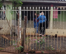 Mãe com uma criança no colo recebendo pão atrás do portão