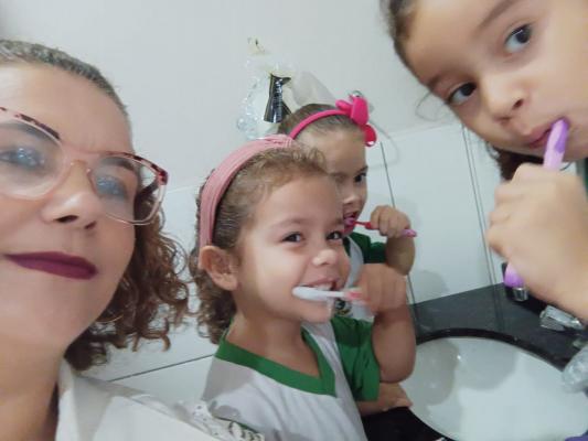 Auxiliar Bucal realizando trabalho de saúde bucal com as crianças.
